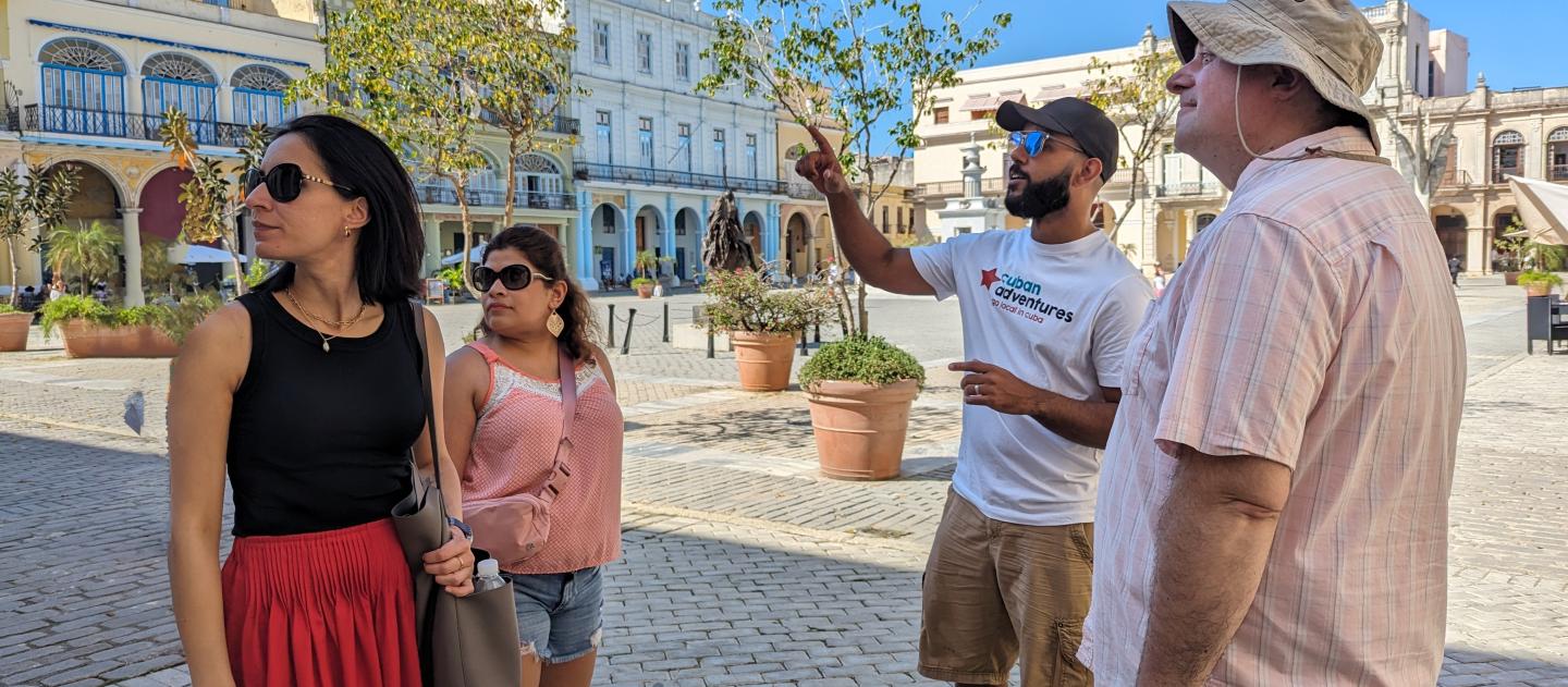 A Cuban Adventures tour guide points out Plaza Vieja highlights to a small group of tourists